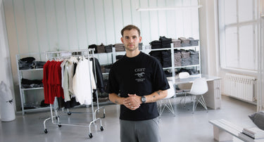 GRIT founder Noah Kolbe photographed inside the Berlin office – wearing GRIT clothes surrounded by neatly folded collections and clean showroom interior