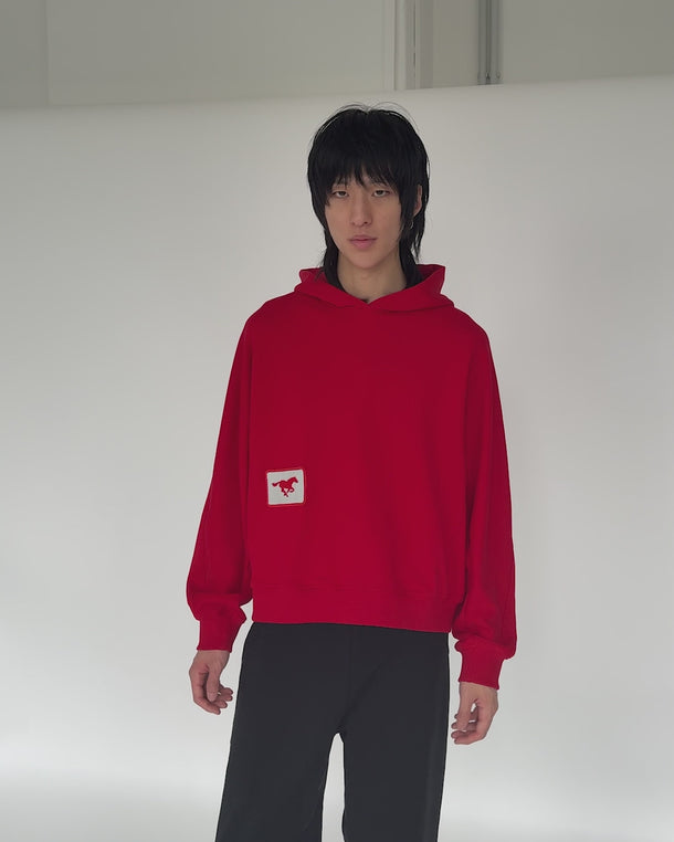 Model wearing red GRIT hoodie reveals hidden hood drawstrings and adjusts hood fit – interactive streetwear detail shown in motion for premium unisex hoodie
